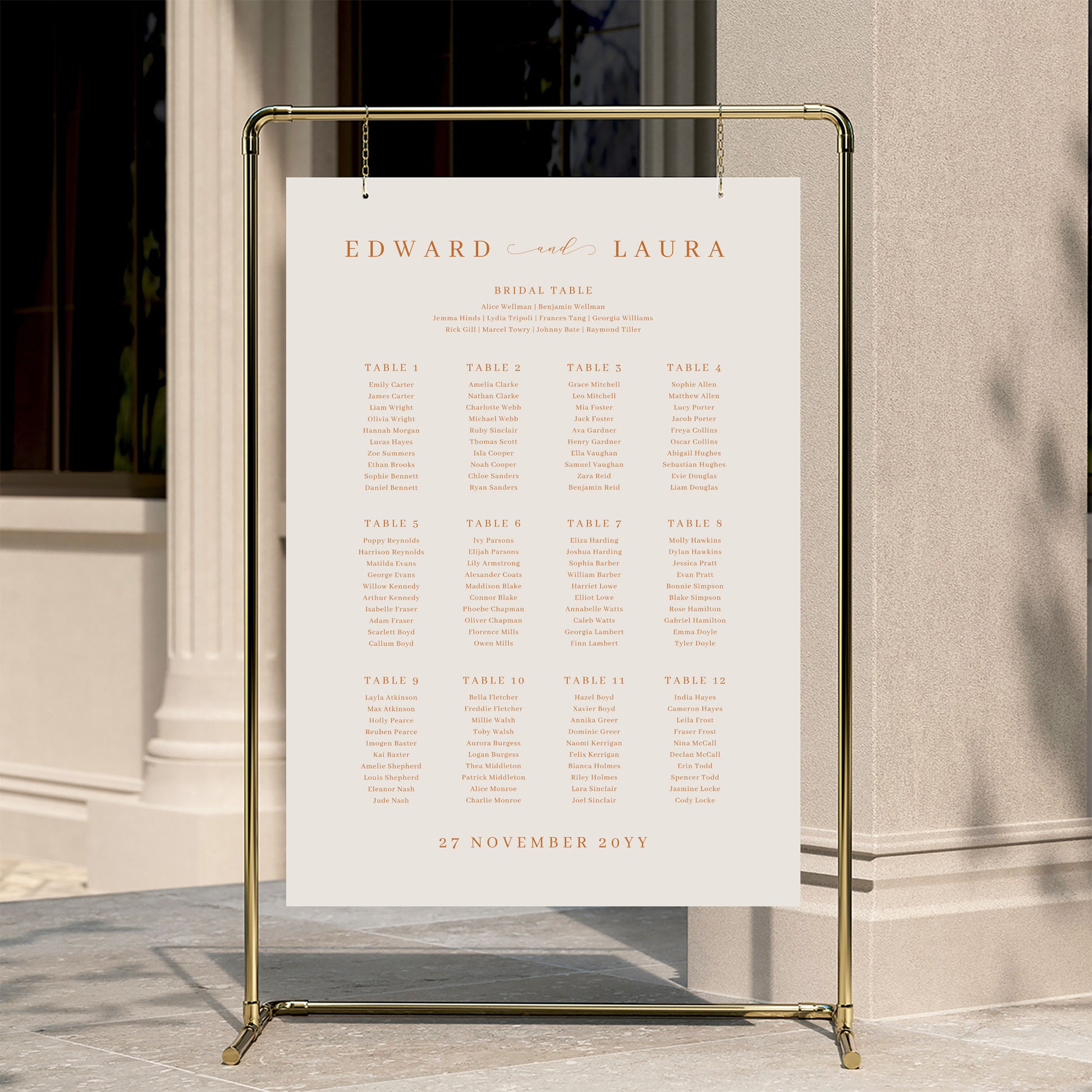 Minimal wedding seating chart template displayed on a gold stand against a neutral wall.
