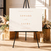 Modern welcome sign template on an easel with floral arrangements and candles in a decorative setting.