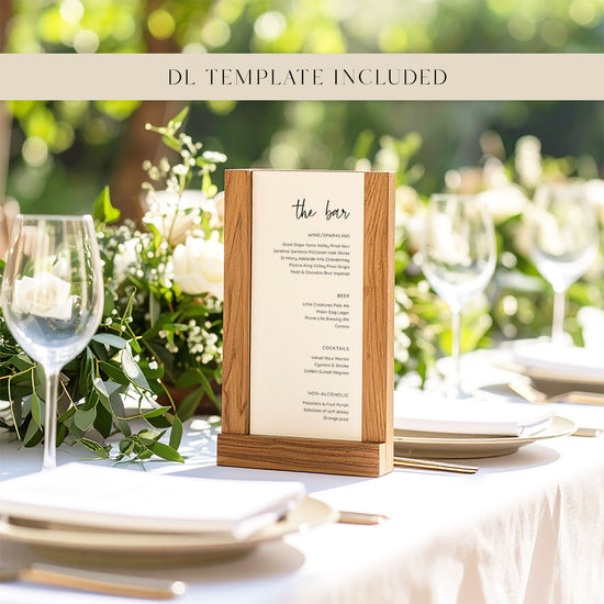 Table setting with a wooden menu holder displaying 'the bar' on a blurred natural background