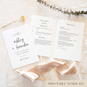 Modern A5 wedding Mass ceremony booklet shown open with the cover beside it, styled on light fabric with dried florals and a soft ribbon.