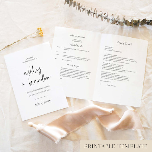 Modern A5 wedding Mass ceremony booklet shown open with the cover beside it, styled on light fabric with dried florals and a soft ribbon.