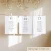Three white seating chart cards with printed names, clipped to a string with pegs, against a neutral background.