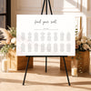 Modern seating chart template on an easel with floral arrangements and candles in a decorative setting.