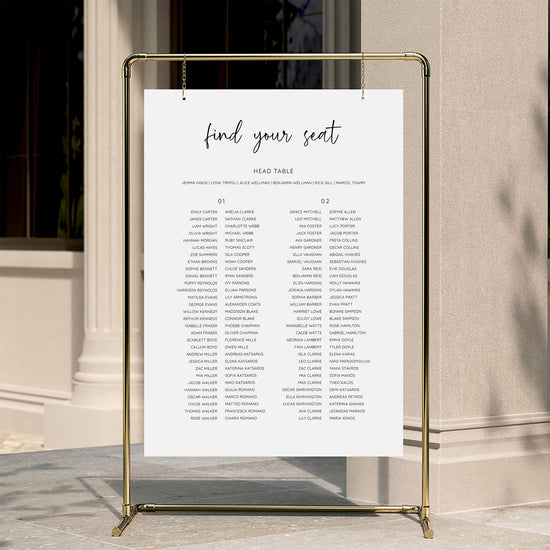 Minimal wedding seating chart template displayed on a gold stand against a neutral wall.
