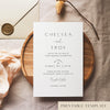 Wedding invitation template design on a white card sitting on a wooden plate with decorative elements.