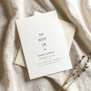 Minimal bridal shower invitation on textured card with envelope on fabric background.