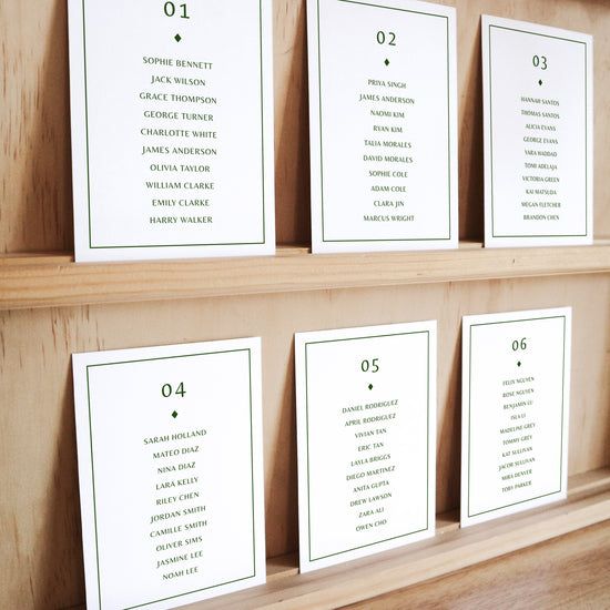 Set of six printable seating chart cards with names on a wooden display shelf.