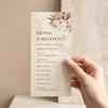 Hand holding a DIY boho wedding ceremony program template with dried floral arrangement, earthy watercolour texture and order of events listing.