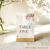 Printable table number card displayed on a wooden stand on a linen table cloth.