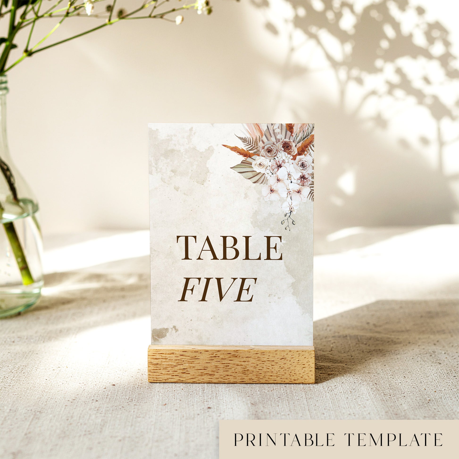 Printable table number card displayed on a wooden stand on a linen table cloth.