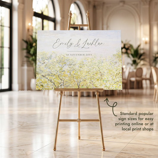 Butter yellow fine art welcome sign featuring Monet's blossoming fruit trees, set on an ornate gold easel in a grand arched reception hall.