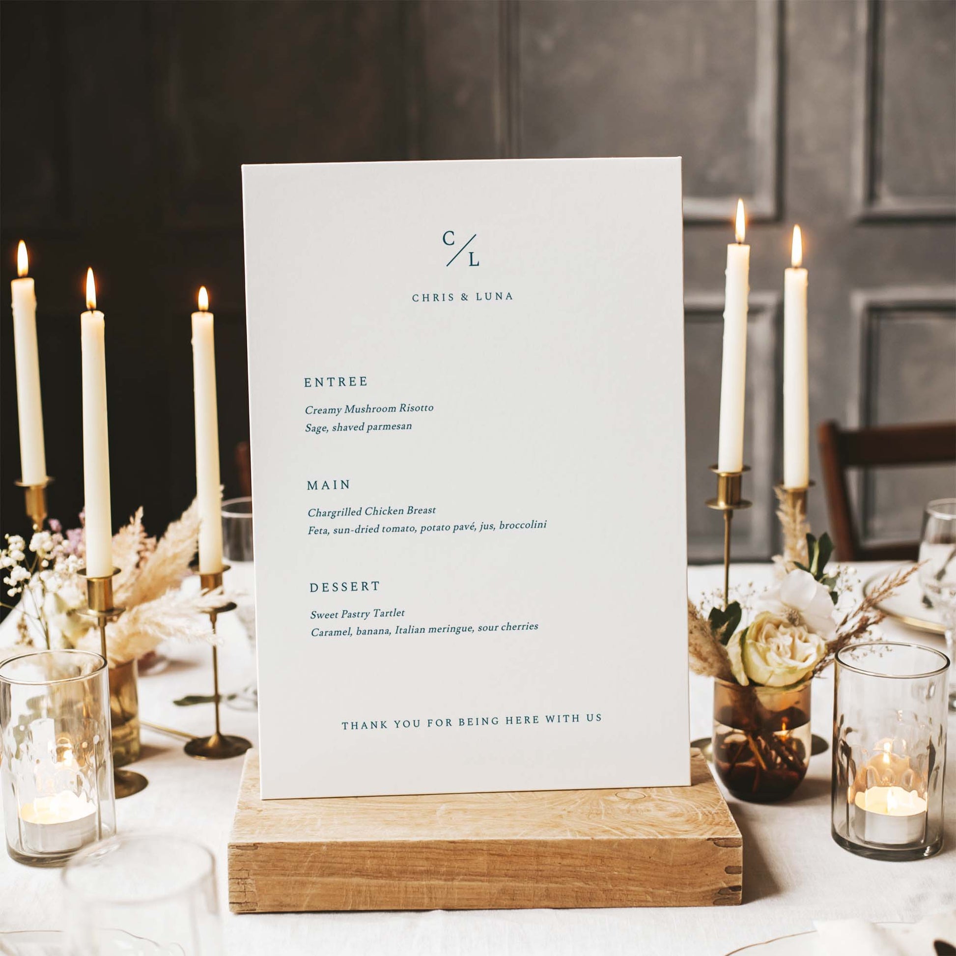 Wedding menu card on a wooden stand with candles and flowers in the background.