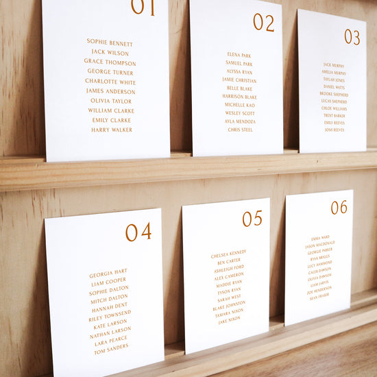 Set of six printable seating chart cards with names on a wooden display shelf.