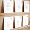 Set of six printable seating chart cards with names on a wooden display shelf.
