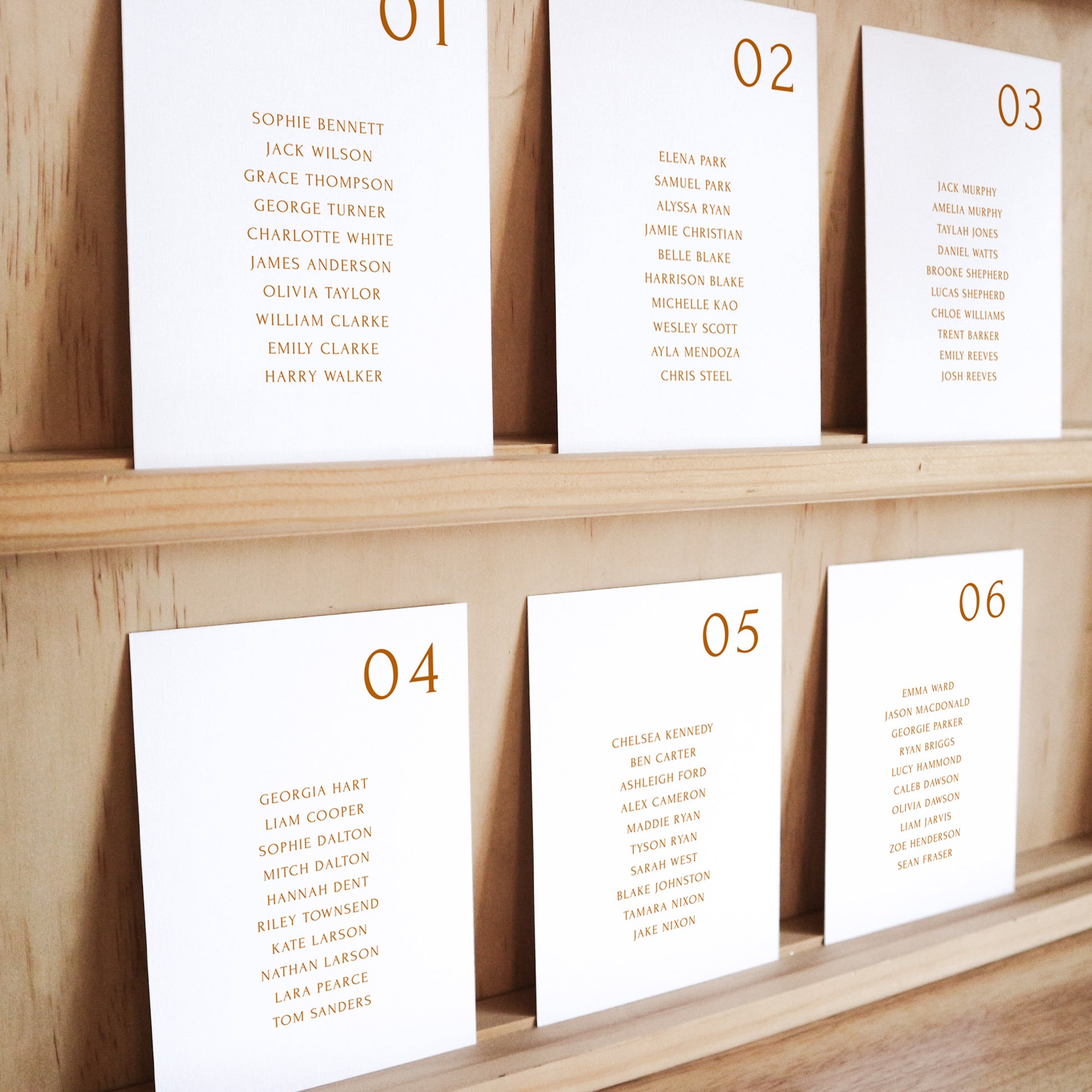 Set of six printable seating chart cards with names on a wooden display shelf.
