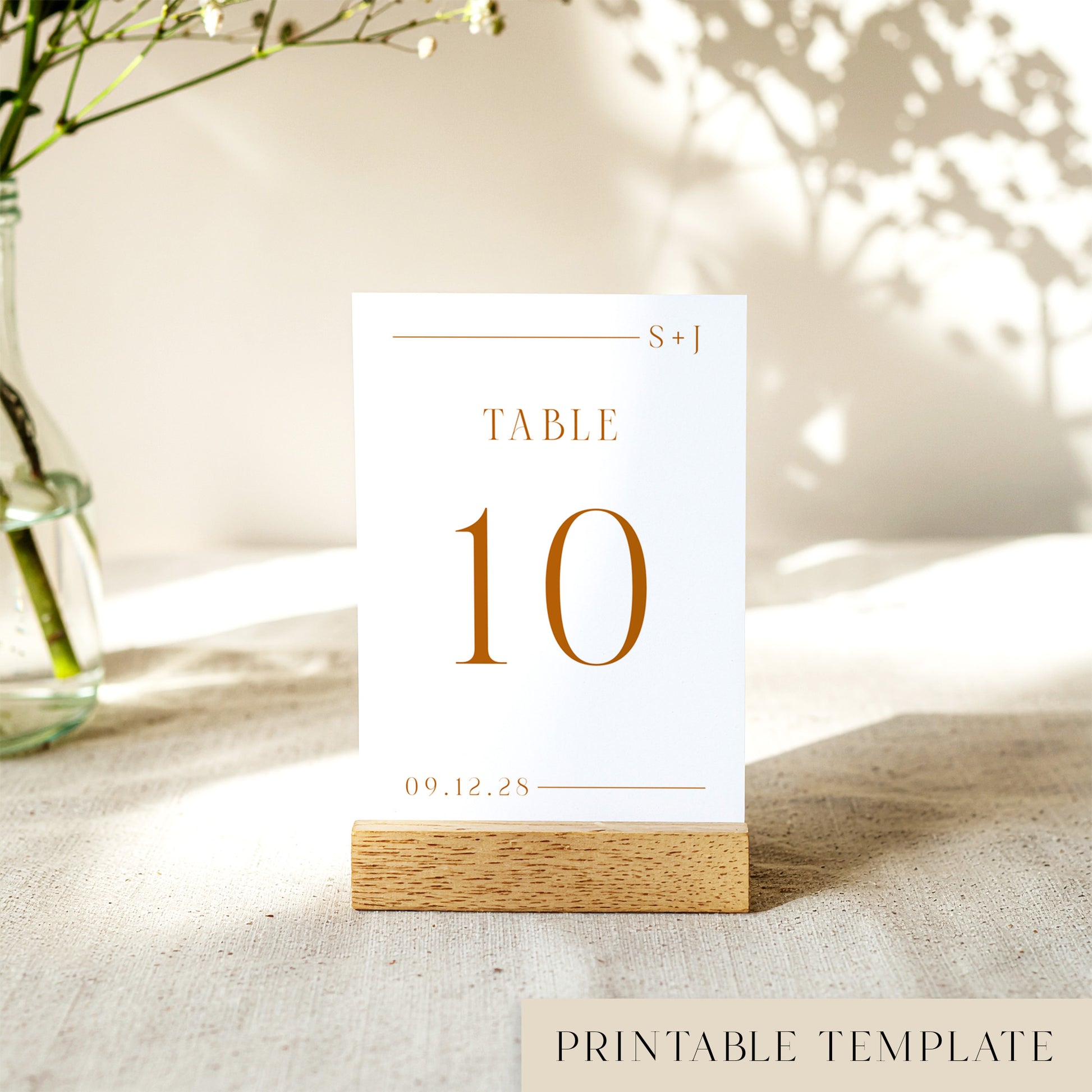Printable table number card displayed on a wooden stand on a linen table cloth.