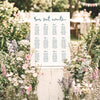 DIY whimsical wedding seating chart template styled at an outdoor wedding surrounded by wildflowers and greenery.