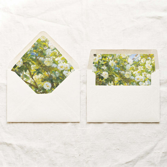 DIY fine art garden roses envelope liners in a euro flap and a straight flap, with a Krøyer painting of white and ivory blooms, sunlit foliage and touches of periwinkle blue for 5x7 wedding invitations.